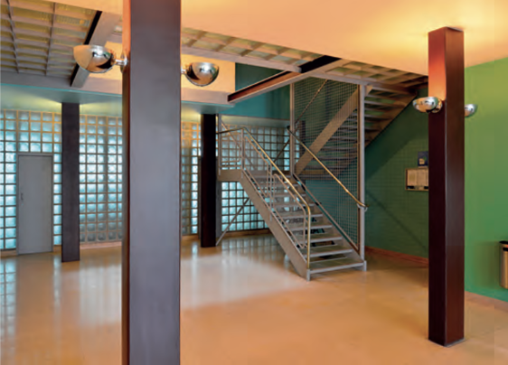 Moderner Innenbereich mit Metalltreppe, Glasbausteinwand, Säulen und warmem Licht, Corbusier